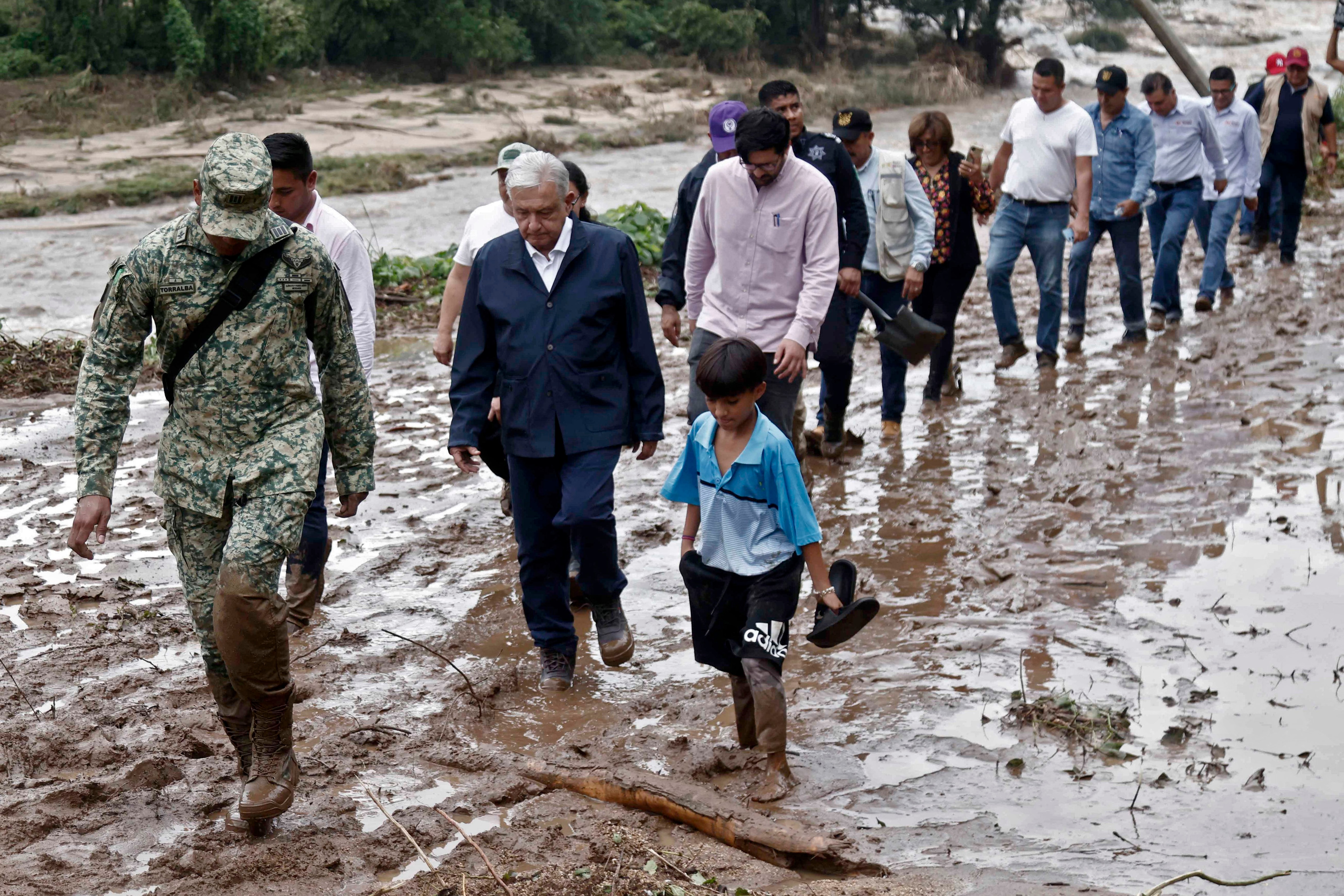 El presidente López Obrador  y miembros de su gabinete caminan sobre el fango mientras visitan la comunidad El Kilometro 42, cerca de Acapulco (Foto: AFP)